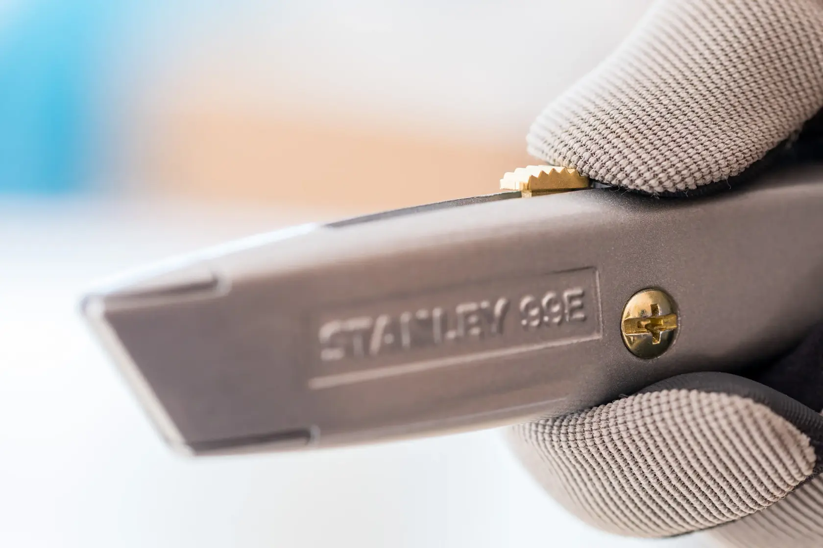 STANLEY 1-10-099 Universalmesser Nahaufnahme, gehalten in Handschuh, zeigt Schieberegler und Schraube.