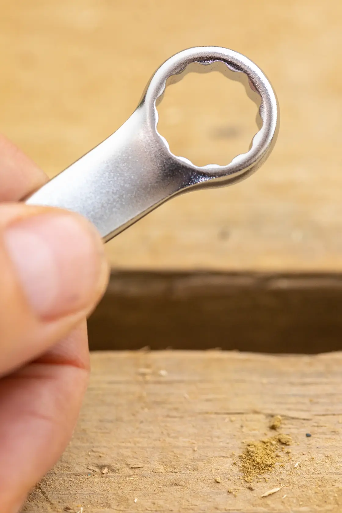 STANLEY FMMT13031-0 box-end wrench close-up held by hand, silver finish, photography on wood surface.