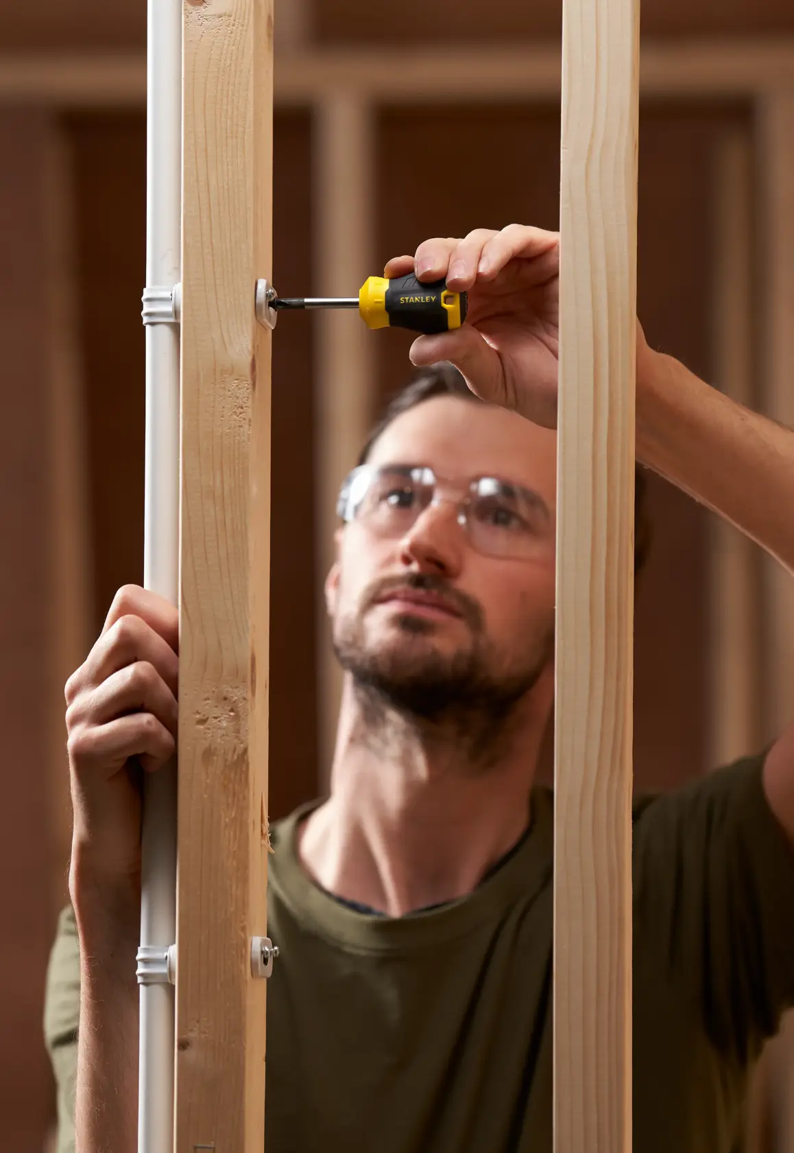Photo of STANLEY STHT16154-0 screwdriver in use on wooden framing, close-up action shot.