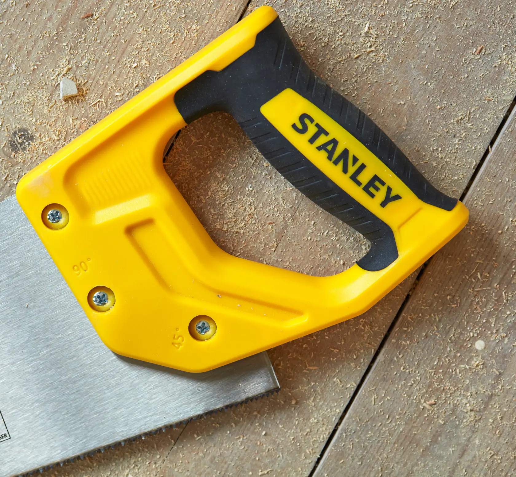STANLEY STHT20370-1 yellow and black hand saw handle on wooden surface, close-up angle.