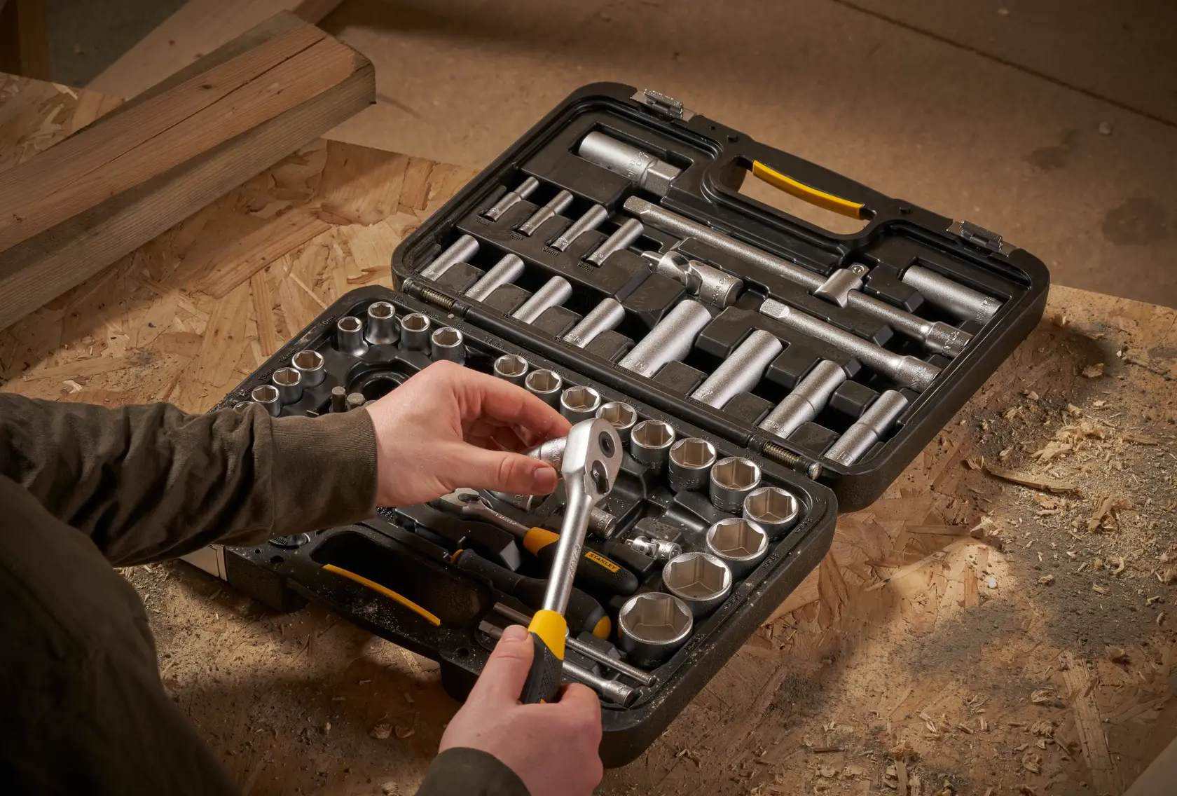 STANLEY STMT17379-1 socket set in black case, person holding ratchet on workbench.