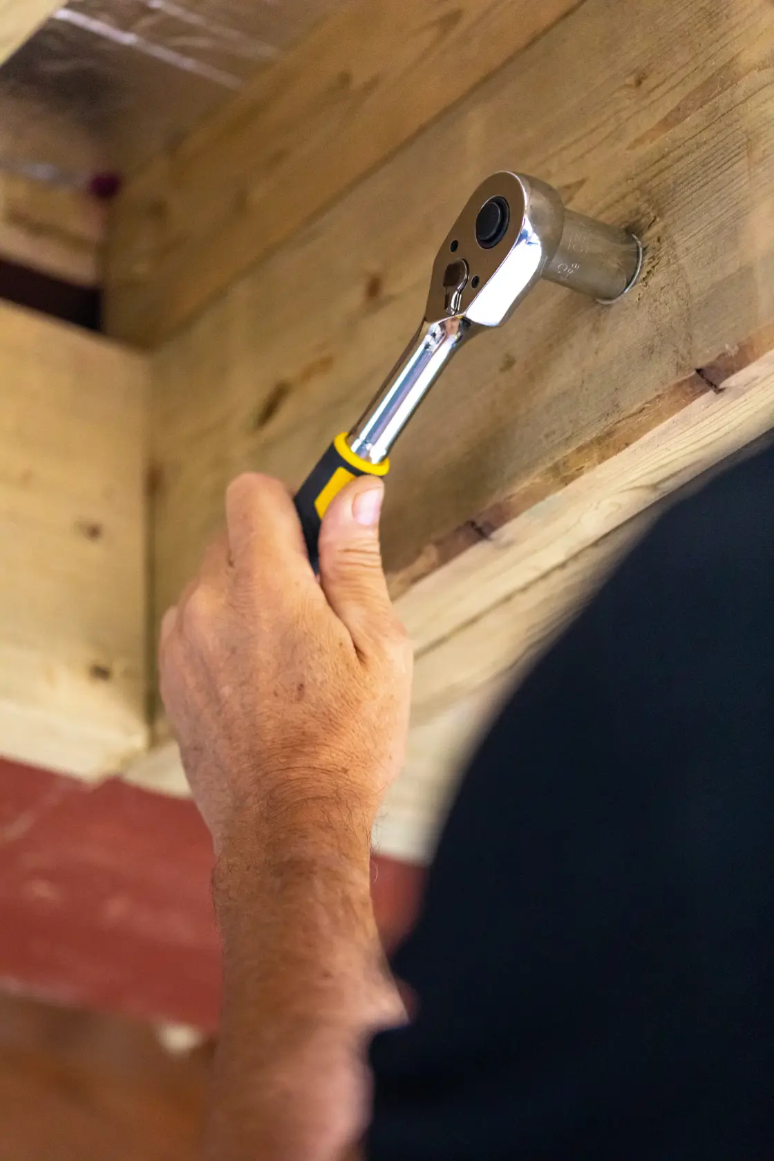 STANLEY STMT17379-1 ratchet wrench in use tightening bolt on wood beam, close-up view.