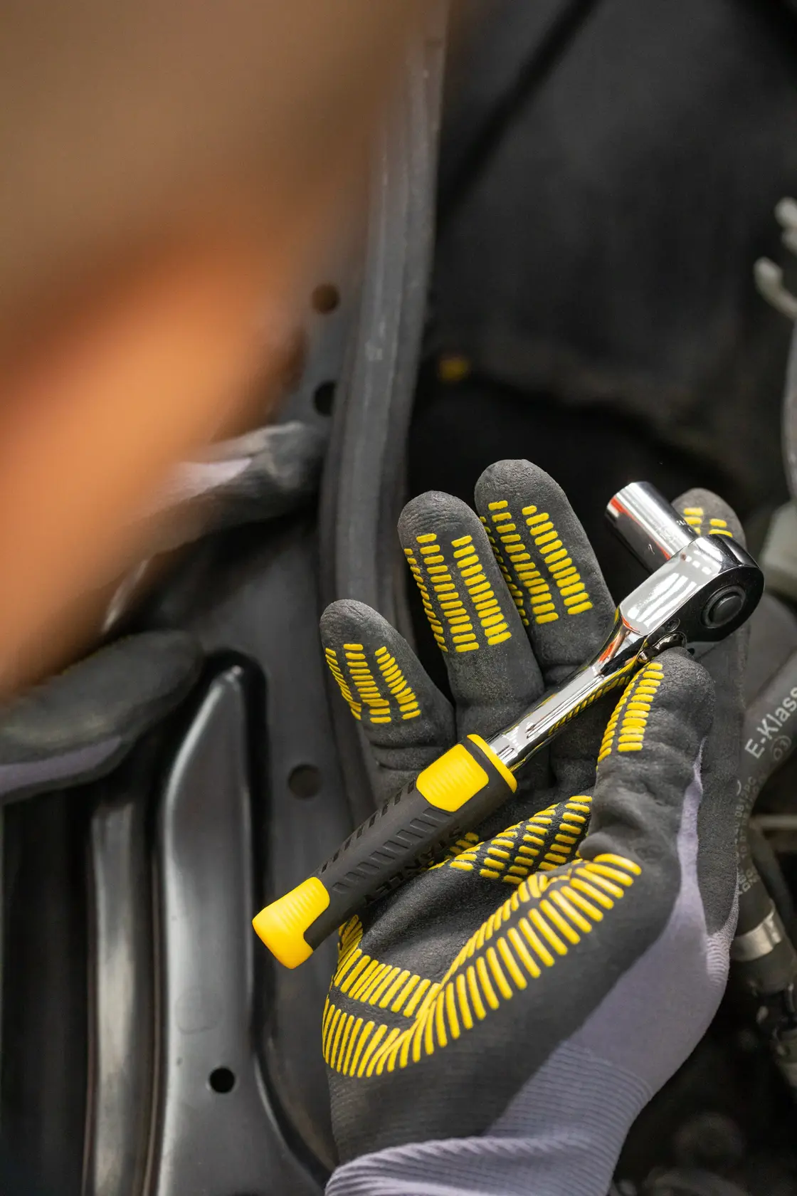 STANLEY STMT82663-0 Ratschenschlüssel mit gelb-schwarzem Griff in behandschuhter Hand bei der Verwendung.