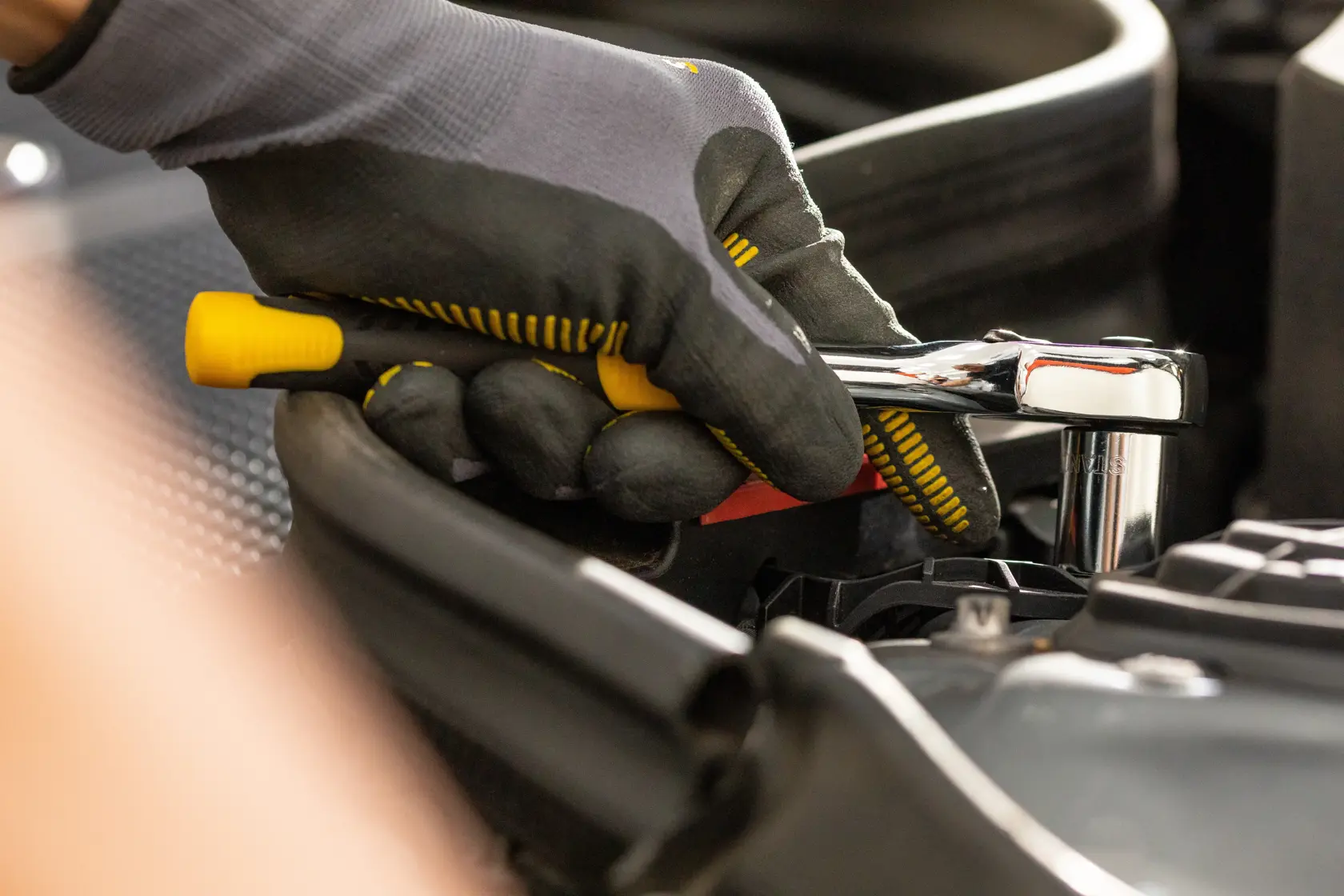STANLEY STMT82664-0 Ratschen-Schlüssel im Einsatz, Nahaufnahme einer Hand mit Handschuh, Automobil-Kontext.
